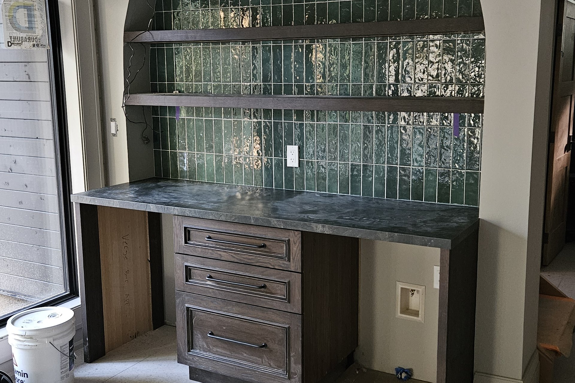 Interior — Finishing A built-in desk area with shelves and a green tiled backsplash, indicating a craft or office space.